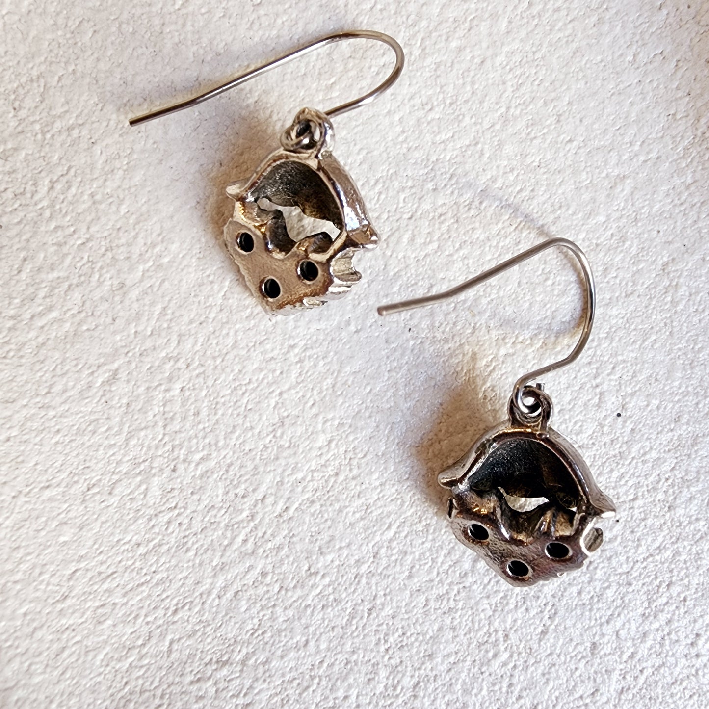 Back view of Martinia silver drop earrings with boho-inspired design on textured background.