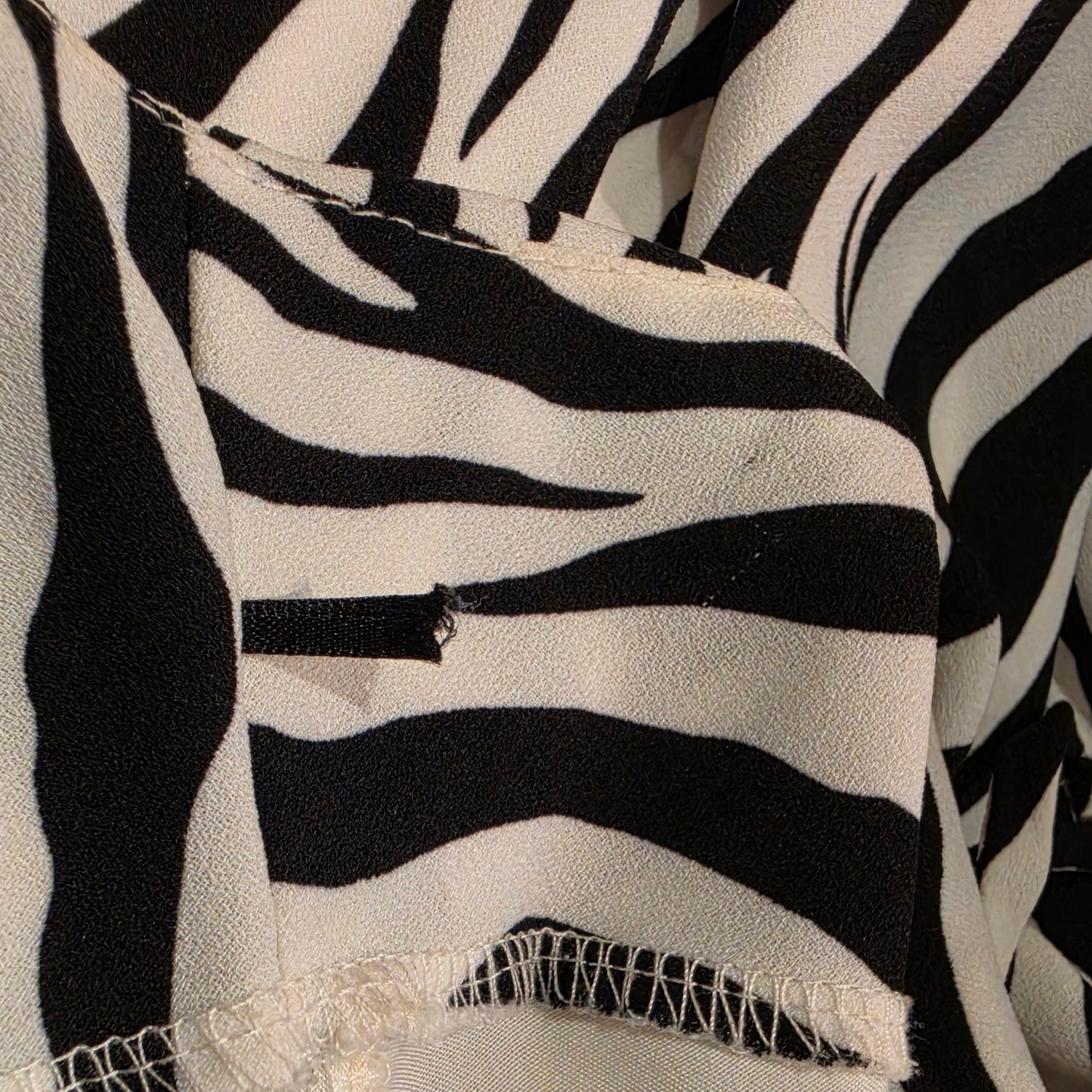 Image showing a close up of a trimmed coat hanger tab and a tiny hole and pull in the fabric nearby