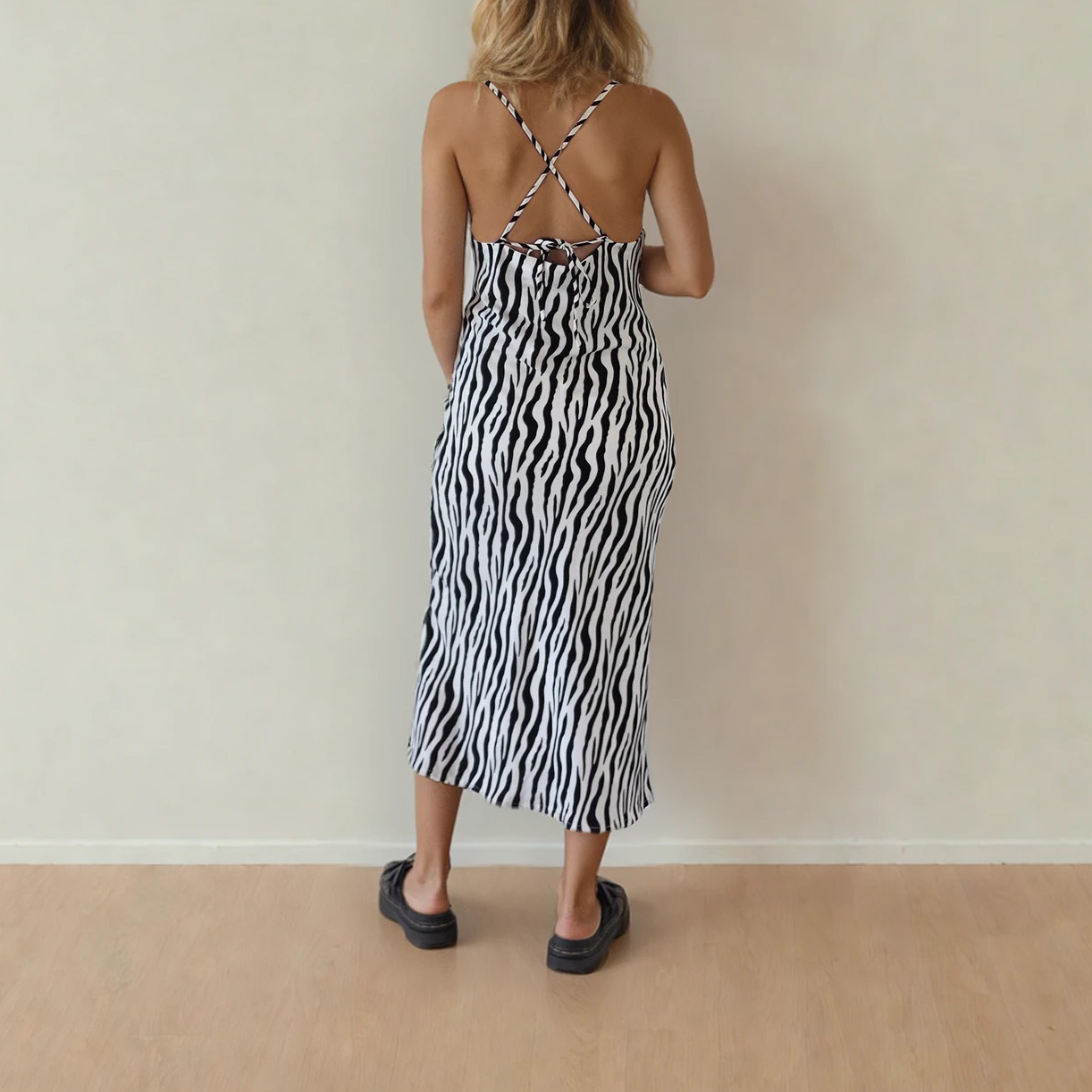 Back view of woman wearing the zebra print midi dress, showing thr crossover back and adjustable tie