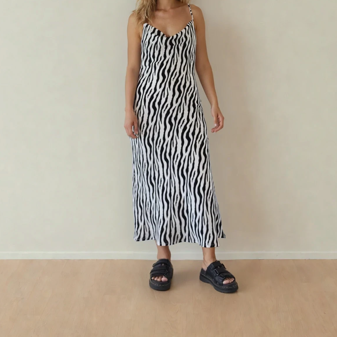 A woman wearing the zebra print midi dress standing against a plain wall.