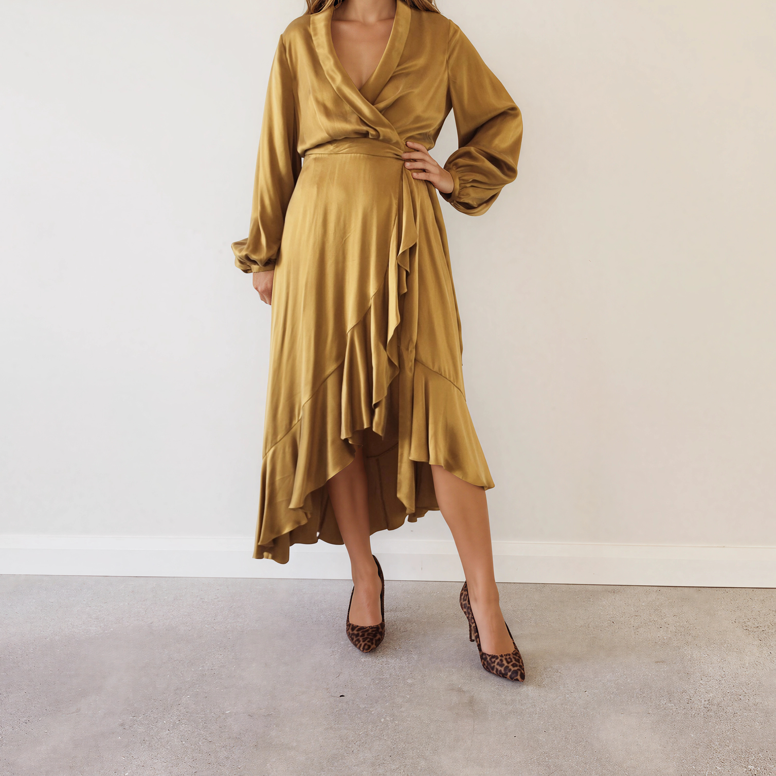 Image of a model in the Zimmermann long-sleeved, wrap-style silk midi dress in a shiny mustard-gold fabric